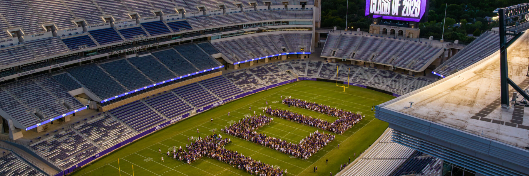 First-year students in the class of 2029 arrange themselves on the playing field of Amon G. Carter Stadium to spell out TCU in giant letters.