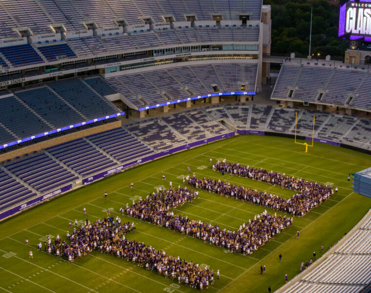 First-year students in the class of 2029 arrange themselves on the playing field of Amon G. Carter Stadium to spell out TCU in giant letters.